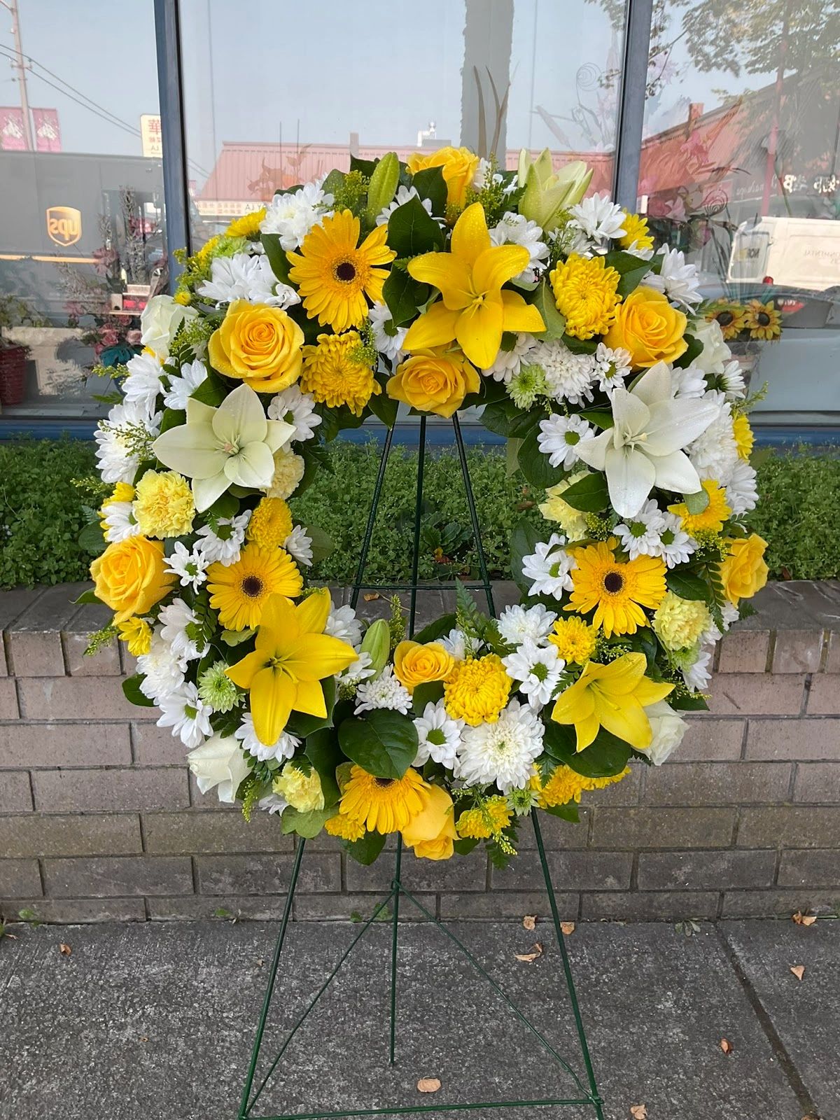 Yellow and white floral wreath on a stand.