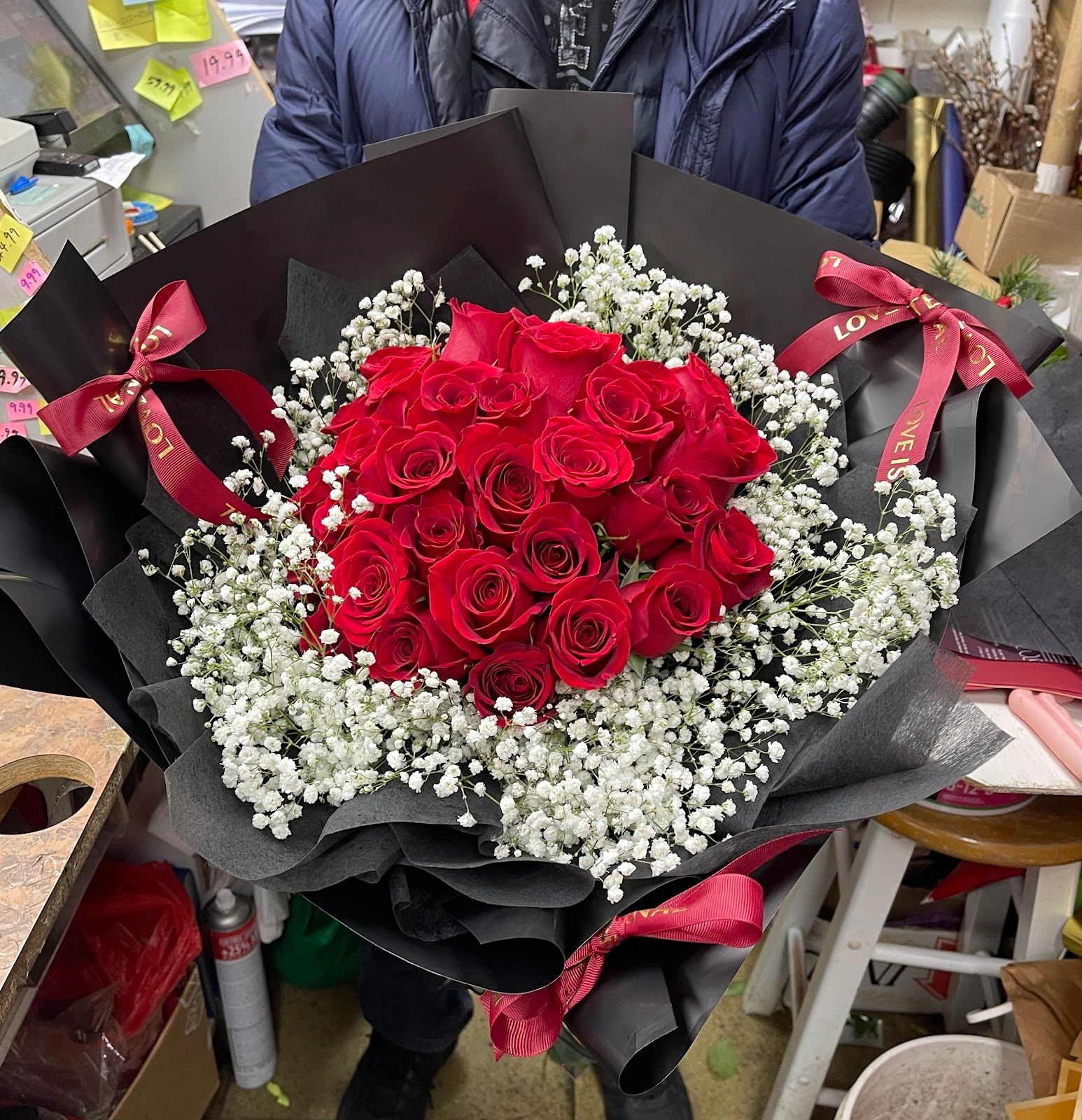 Bouquet of red roses with white baby's breath wrapped in black paper.