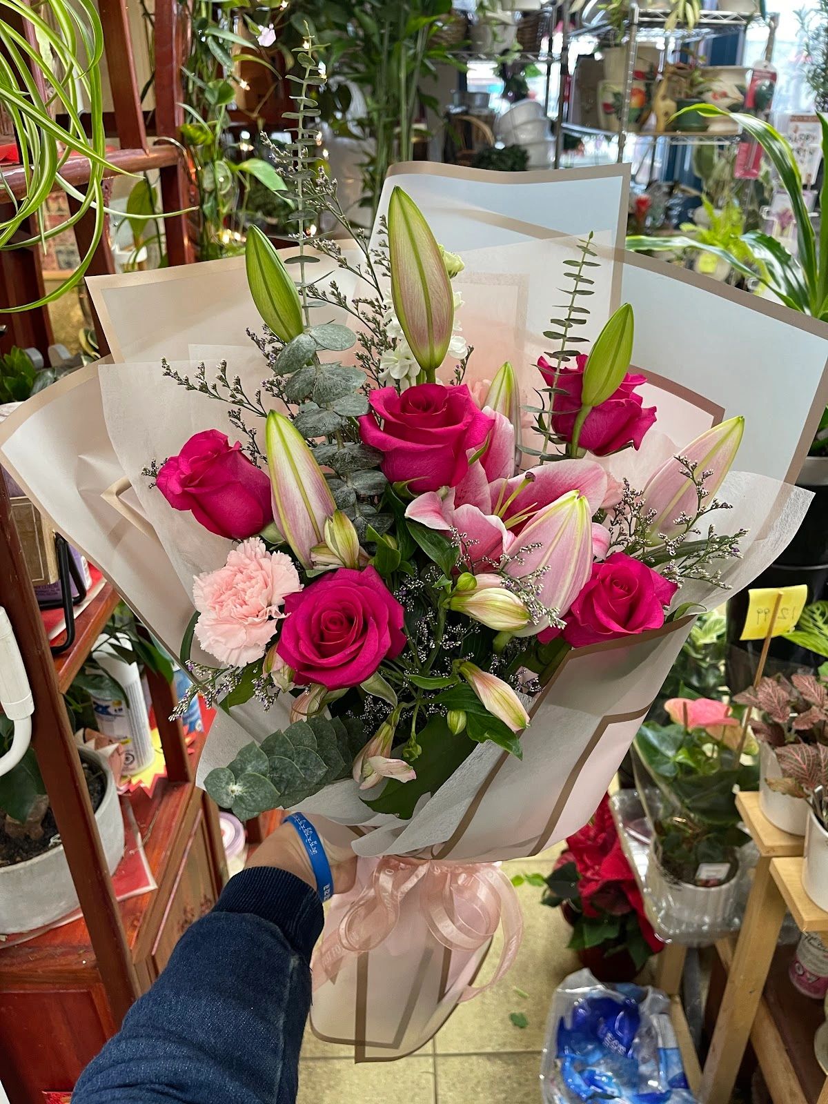 Hand holding a bouquet of pink roses and lilies.