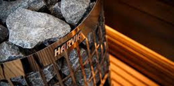 Close-up of a sauna heater filled with stones and wooden bench.