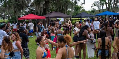 Crowd enjoying an outdoor summer event with colorful tents.