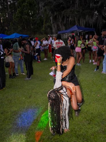 People enjoying an outdoor party with dancing and colorful lights on the grass.