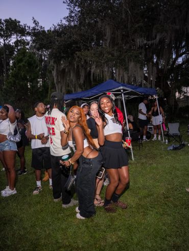 Three friends posing happily at an outdoor event during dusk.