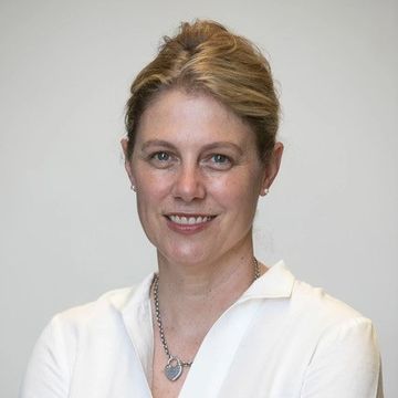 Portrait of a smiling woman with blonde hair and white shirt.