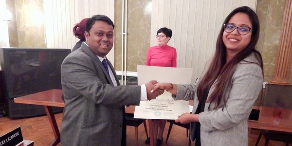 Two people shaking hands during a certificate presentation.
