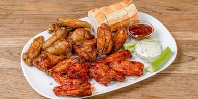 18 Chicken Wings mit Brot, Sellerie und 2 Dips auf einem Teller