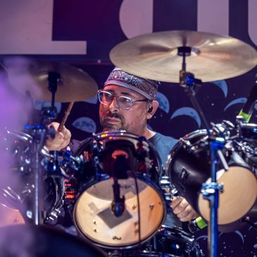 Drummer immersed in performance on stage with cymbals and drums.