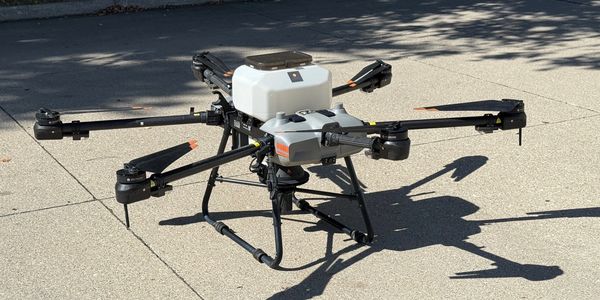 A large quadcopter drone with extended arms and propellers on a concrete surface.