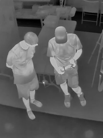 Two people standing and looking at a device indoors on a mat labeled SRT.