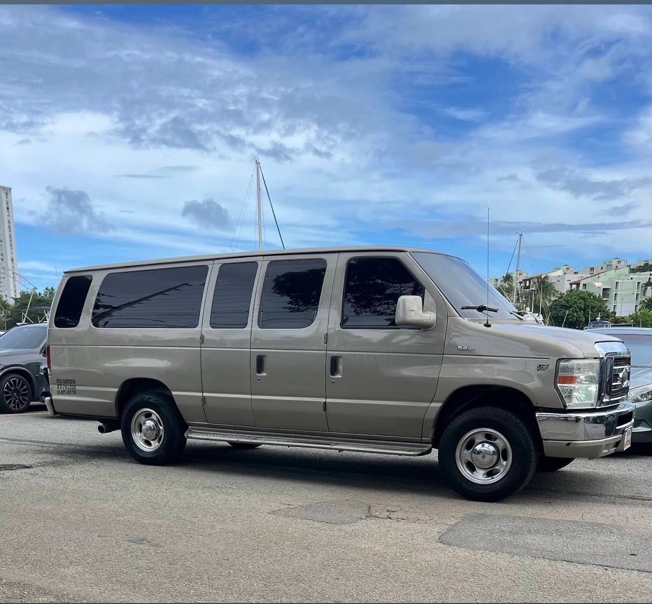 Large beige van parked on a street under a blue sky.