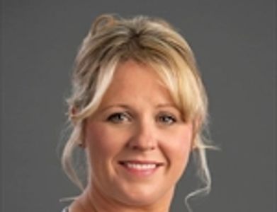 Portrait of a smiling blonde woman with a gray background.