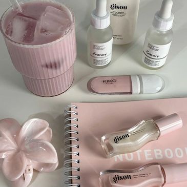 Pink-themed skincare and beauty items with a pink drink on a white surface.
