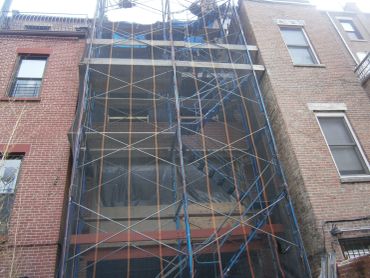 Building covered in scaffolding and netting for construction.