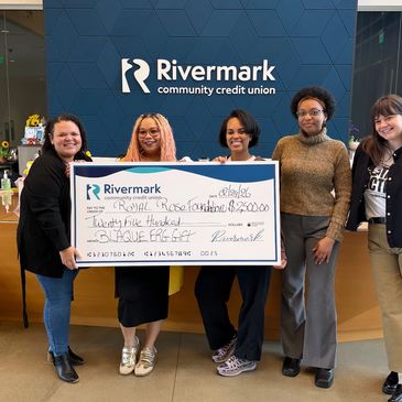 Five women holding a large donation check at Rivermark Credit Union.