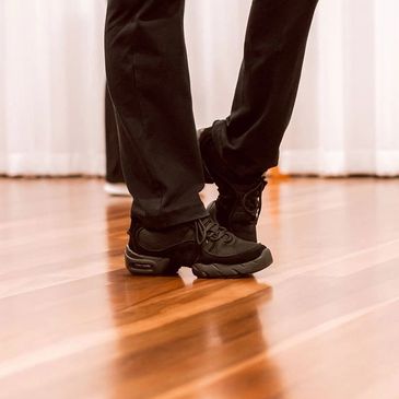 Close up of a dancers feet in dance joggers, poised ready to move.