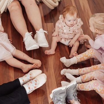 Dancers sitting on floor in circle with legs pointed towards the centre.
