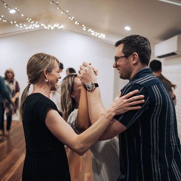 A couple in their dance frame laughing as teacher assists them.