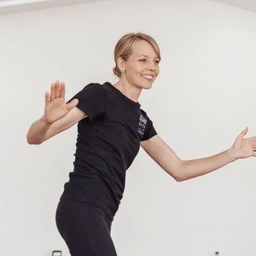 Teacher demonstrating movement, smiling.