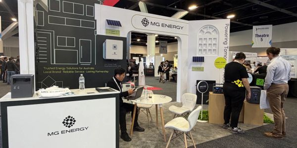 MG Energy booth at an event with company representative and visitors.
