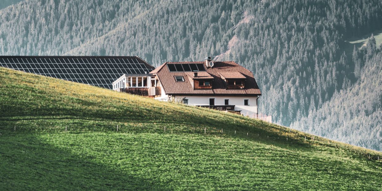 House with solar panels on a green hillside.