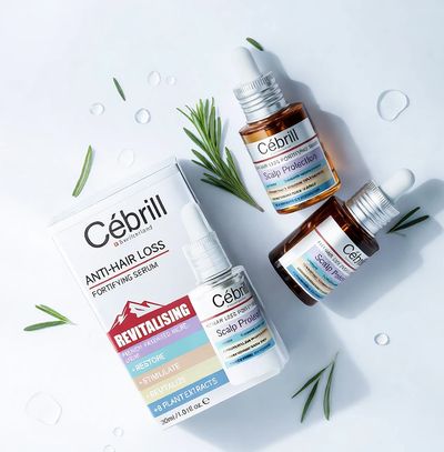 Cébrill anti-hair loss serum and scalp protection products arranged with rosemary sprigs.