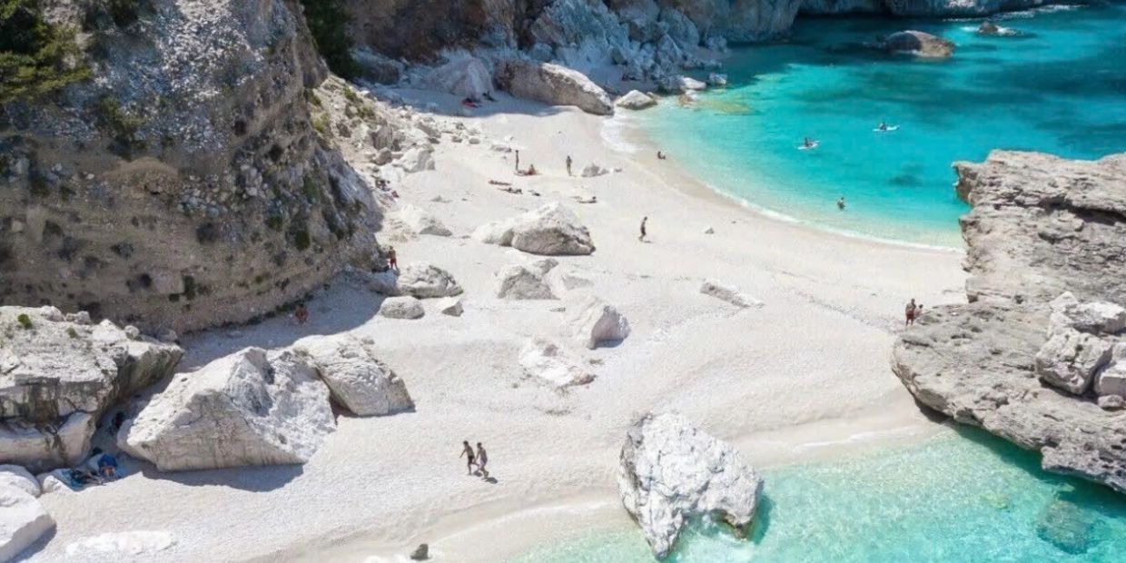 A beautiful beach with clear turquoise water and large rocks.