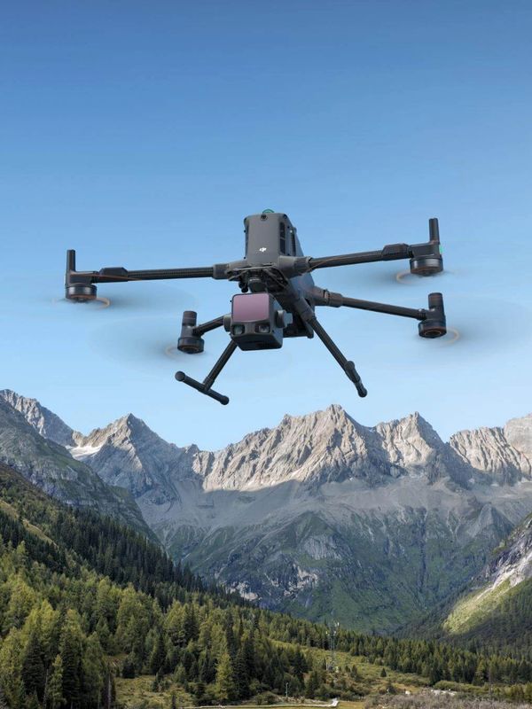 A drone flying over a mountainous landscape with clear blue skies.