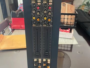 Close-up of an audio mixer with sliders and knobs on a table.