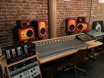 Professional audio mixing console in a studio with vintage speakers and equipment.