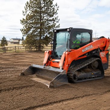 Kubota SVL75 skid steer loader on dirt field.