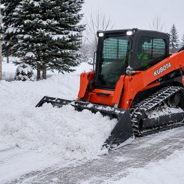Kubota loader clearing snow from a path.