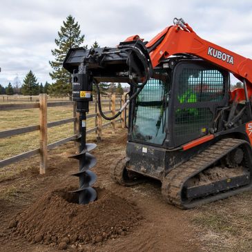 Kubota excavator with auger attachment drilling soil.
