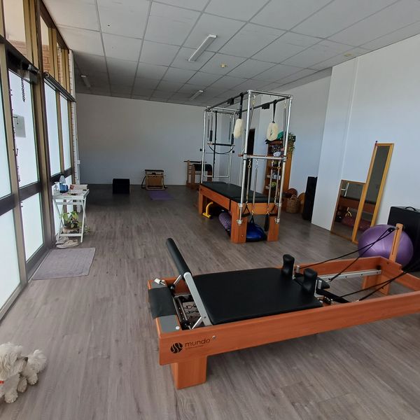 Empty Pilates studio with equipment and natural light.