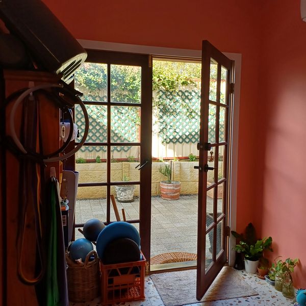 a door of a pilates studio opens up to the courtyard with potted plants 