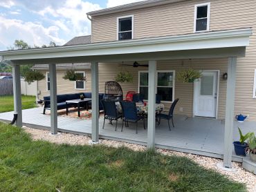 Covered patio with outdoor furniture and hanging plants.