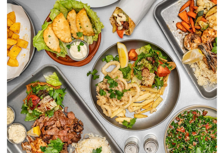 A vibrant spread of Mediterranean dishes including grilled meats, fried calamari, and fresh salads.