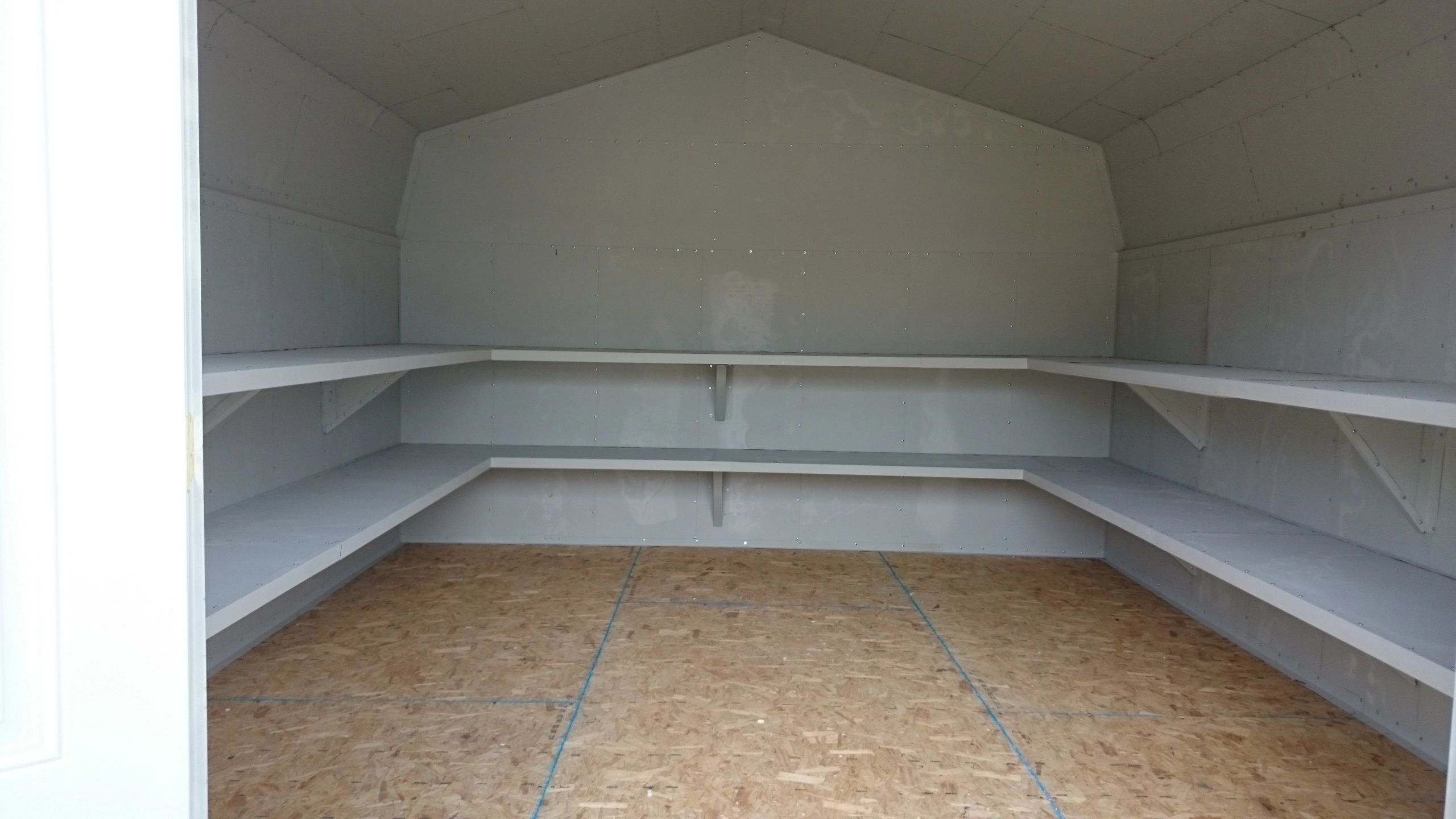 Empty storage shed with corner shelves.