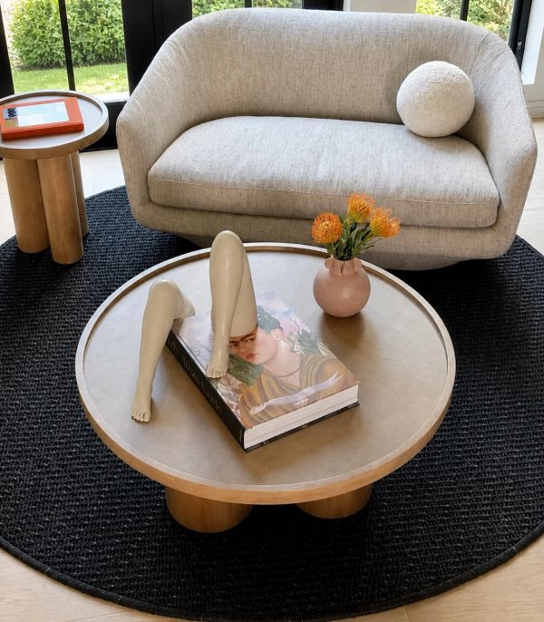 Modern living room with unique leg sculpture on coffee table and cozy beige sofa.