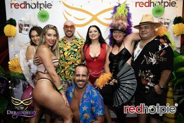 Group of six adults in festive tropical attire posing at a themed party.
