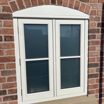 White framed window with frosted glass in a brick wall.