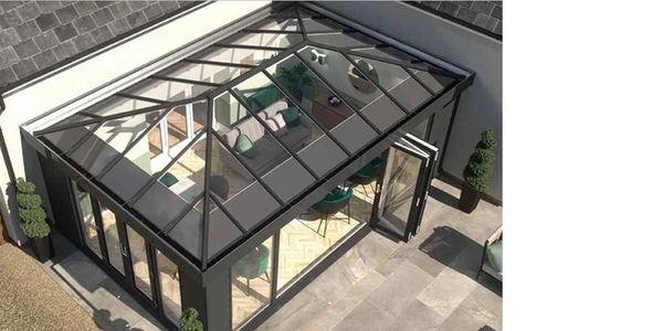 Modern glass conservatory attached to a house with a stylish interior.