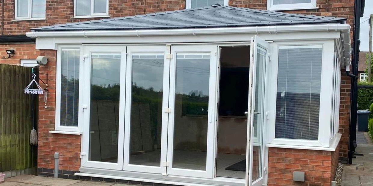 A modern brick house extension with large white-framed glass doors and windows.