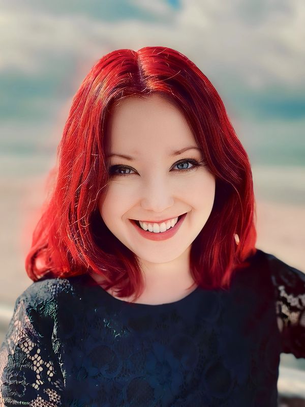 A smiling red-headed woman wearing a black shirt