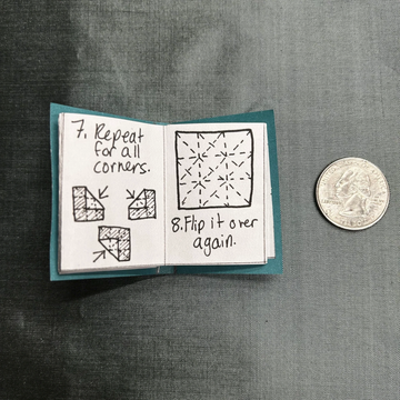 Open miniature book with handwritten instructions beside a quarter.