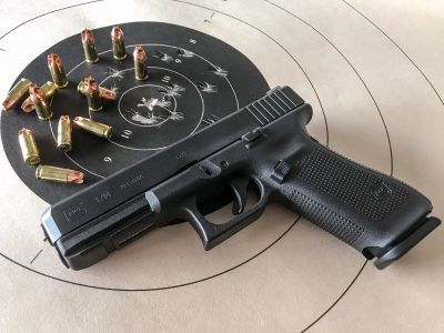 A pistol with bullets on a shooting target.