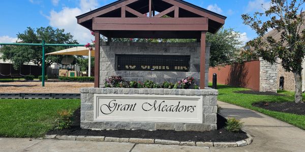 Community entrance sign for Grant Meadows with playground in background.