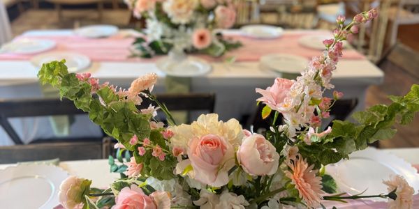 Elegant floral centerpiece with pink and white flowers on a dining table.
