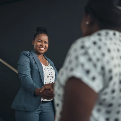 Two professional women shaking hands in a business setting.