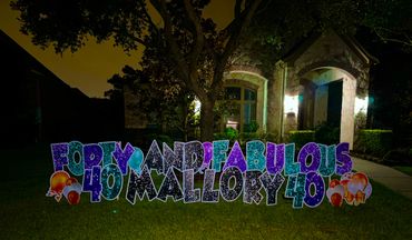 Colorful yard sign celebrating Mallory's 40th birthday at night.