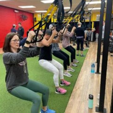 Group doing TRX suspension training in a gym.